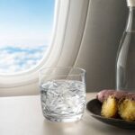 空の旅を思わせる窓辺の焼酎グラスと芋