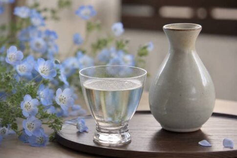 青い花と日本酒のグラスを合わせた春らしい静物