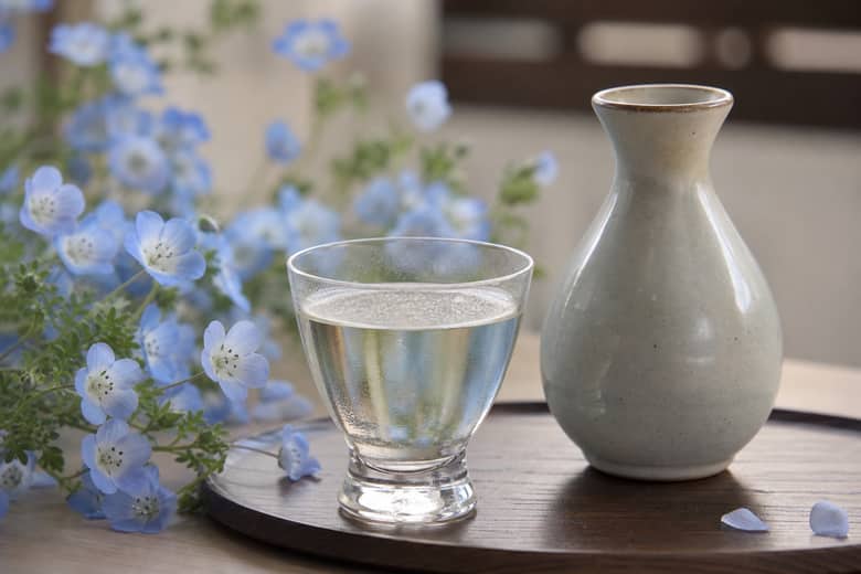 青い花と日本酒のグラスを合わせた春らしい静物